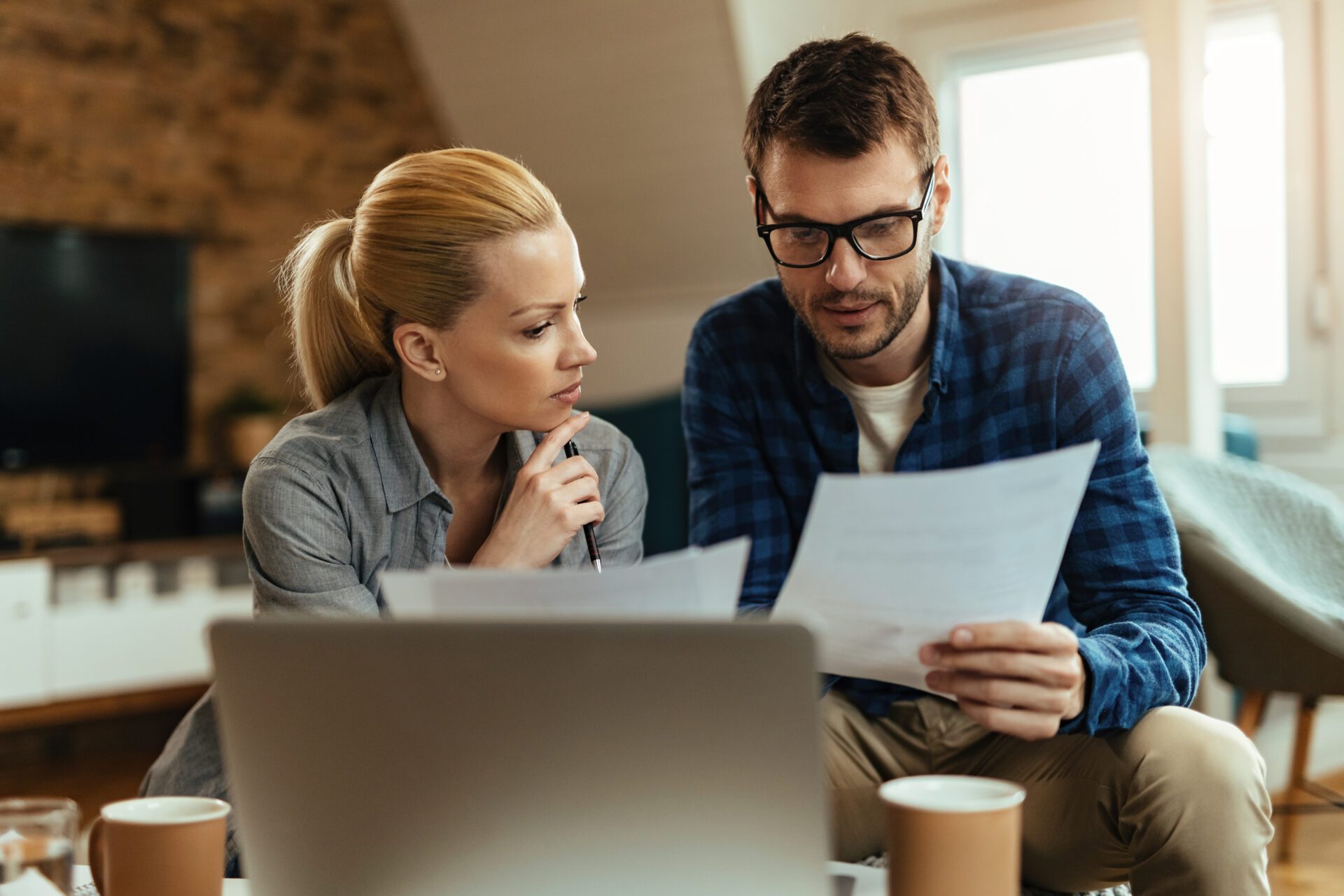 Young couple analyzing their budget while going through home fin Young couple going through their finances while paying bills at home.